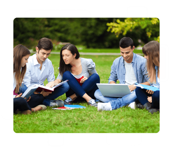 Group of university students looking at books and laptops on lawn