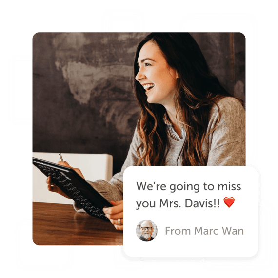Smiling teacher looking at laptop with a "we'll miss you" post