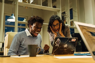 Employees smiling and excited looking at laptop