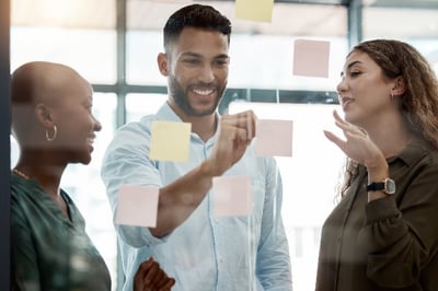 Employees reading shout outs on an employee recognition wall