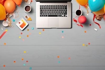 Overhead shot of a laptop with balloons and confetti with a happy work anniversary card