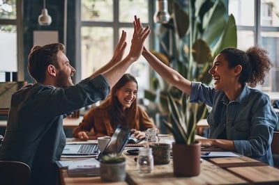 Peer to peer benefits like high fives from two employees while a third smiles in between in the background