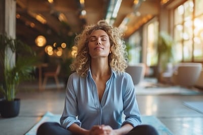 A woman sitting on a yoga mat at work looking serene during National Wellness Month
