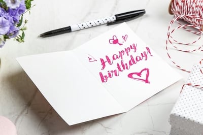 A Happy Birthday message written inside a card, with a pen laid nearby.