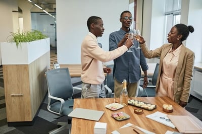 Three employees in a conference room toasting with champagne to a work anniversary