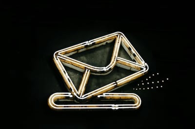 Neon sign featuring an envelope and a paperclip on a black background celebrating ecards