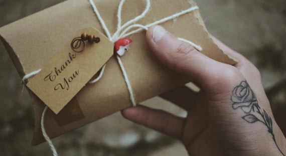 Hand holding an envelope with a thank you tag attached