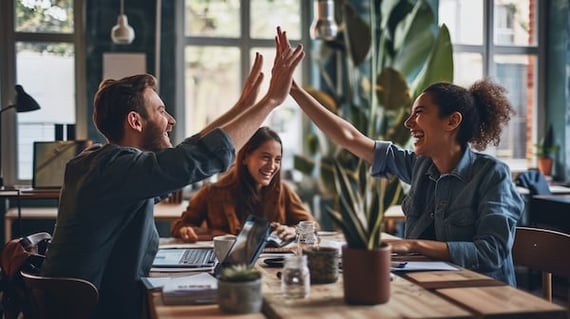 Peer to peer benefits like high fives from two employees while a third smiles in between in the background