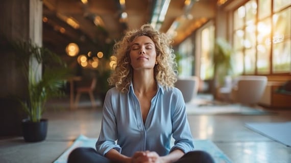 A woman sitting on a yoga mat at work looking serene during National Wellness Month
