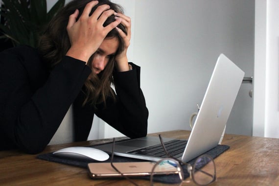 Person holding head in frustration while looking at laptop