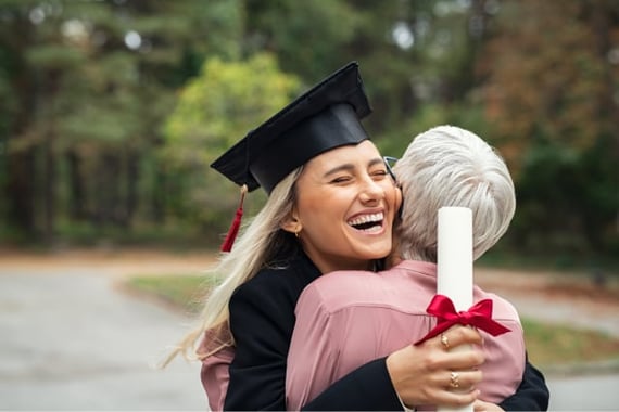 Older person hugging female graduate with diploma