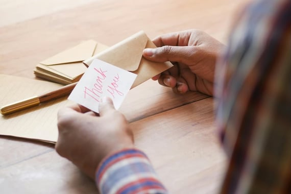 Hands holding an envelope and a card that says "thank you"