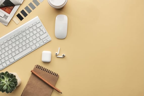 Overhead desk short of a keyboard, mouse, airpods, and a notepad
