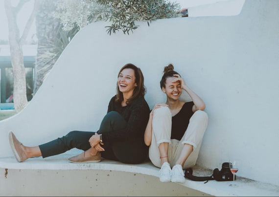 Two friends sitting together and laughing on a bench