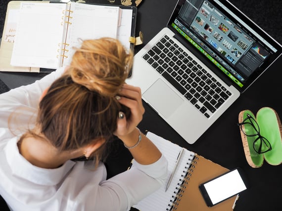 Person putting head in hands while looking at laptop