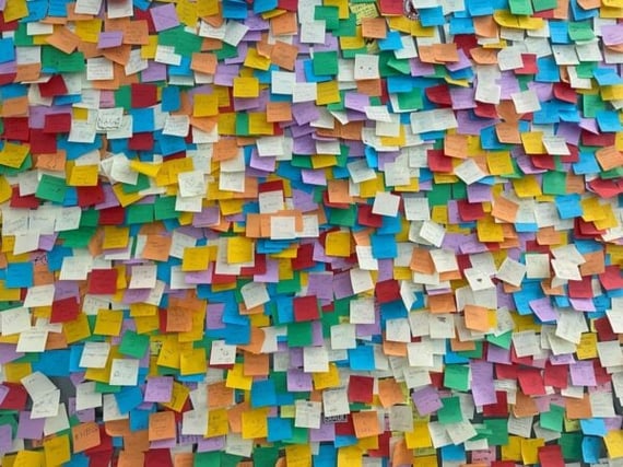 Wall covered in multicolored Post-its, evoking an eCard-style board for employee recognition, staff recognition, and healthcare employee appreciation.