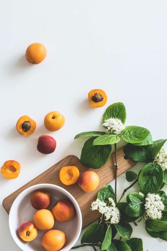Sliced apricots on cutting board with greenery