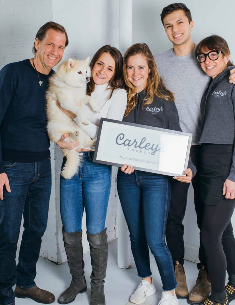 Group of people and dog posing with Carely's Angels sign
