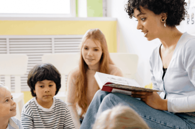 Teacher reading book aloud to group of students