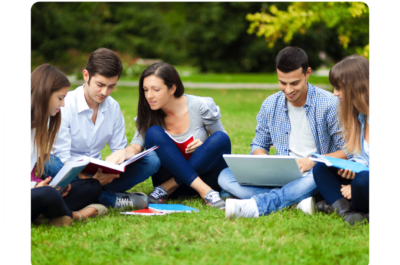 Group of university students looking at books and laptops on lawn