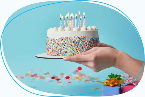 Hands holding birthday cake with lit candles