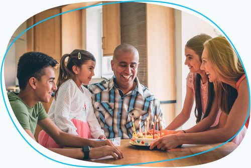 Husband and family celebrating with lit birthday cake