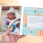 Hand holding an opened Kudoboard book for new baby
