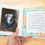 Hand holding opened Kudoboard book to page with post from family