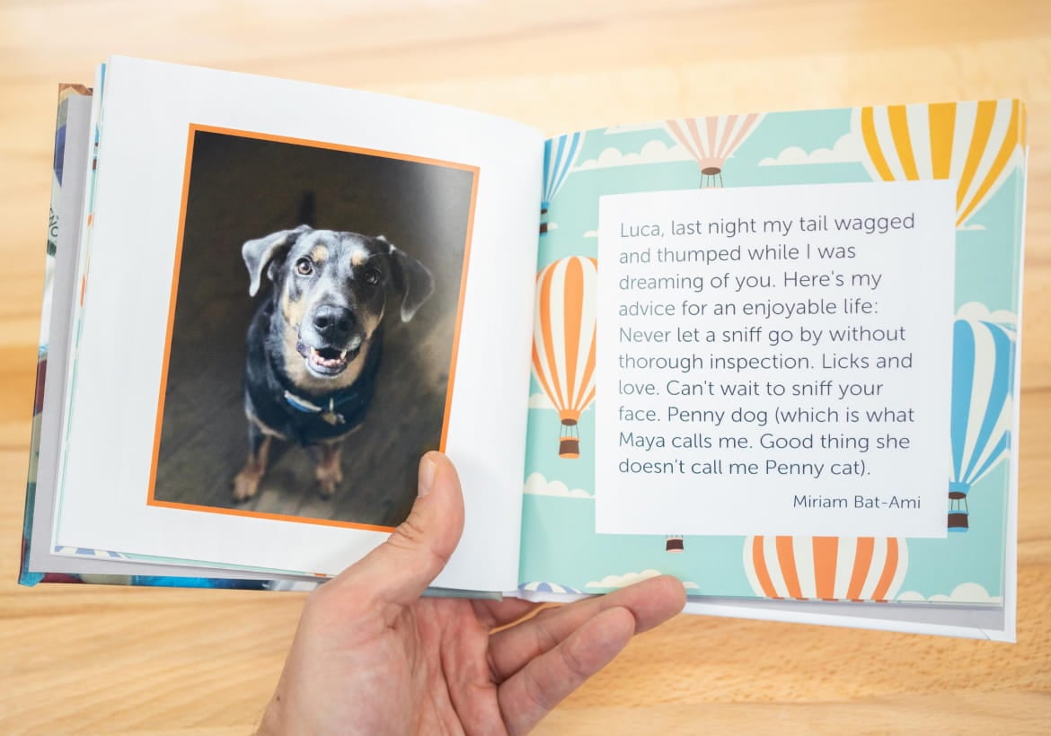 Hand holding opened Kudoboard book to page with post from family