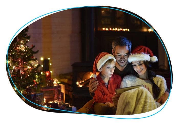 Family looking at tablet in front of Christmas tree