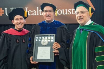 Dean of college holding award with other university executives