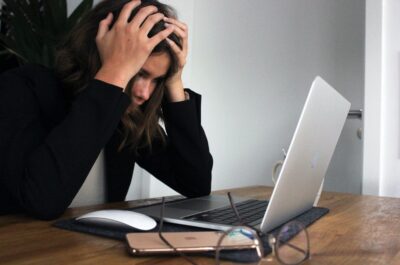 Person holding head in frustration while looking at laptop