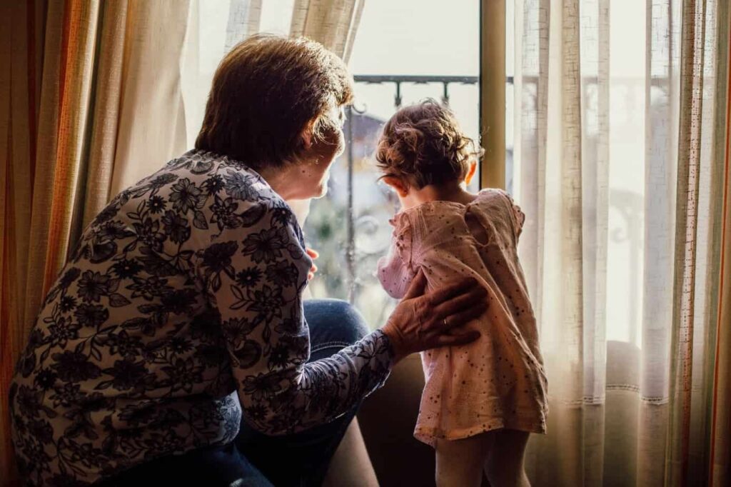Child and grandparent looking out window