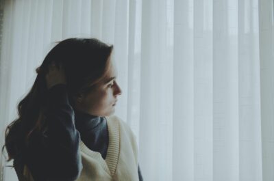 Woman looking down at closed blinds