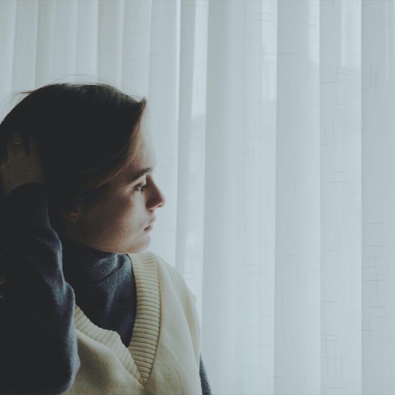 Woman looking down at closed blinds