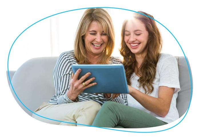 Mother and daughter smiling and looking at tablet