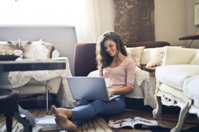 Smiling woman working on laptop on the floor