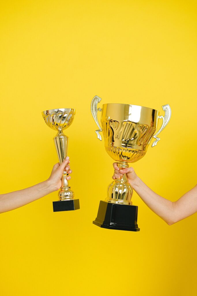 Two hands holding trophies