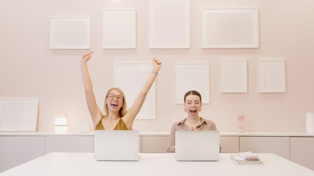 Two office workers celebrating with laptops