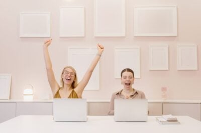 Two office workers celebrating with laptops