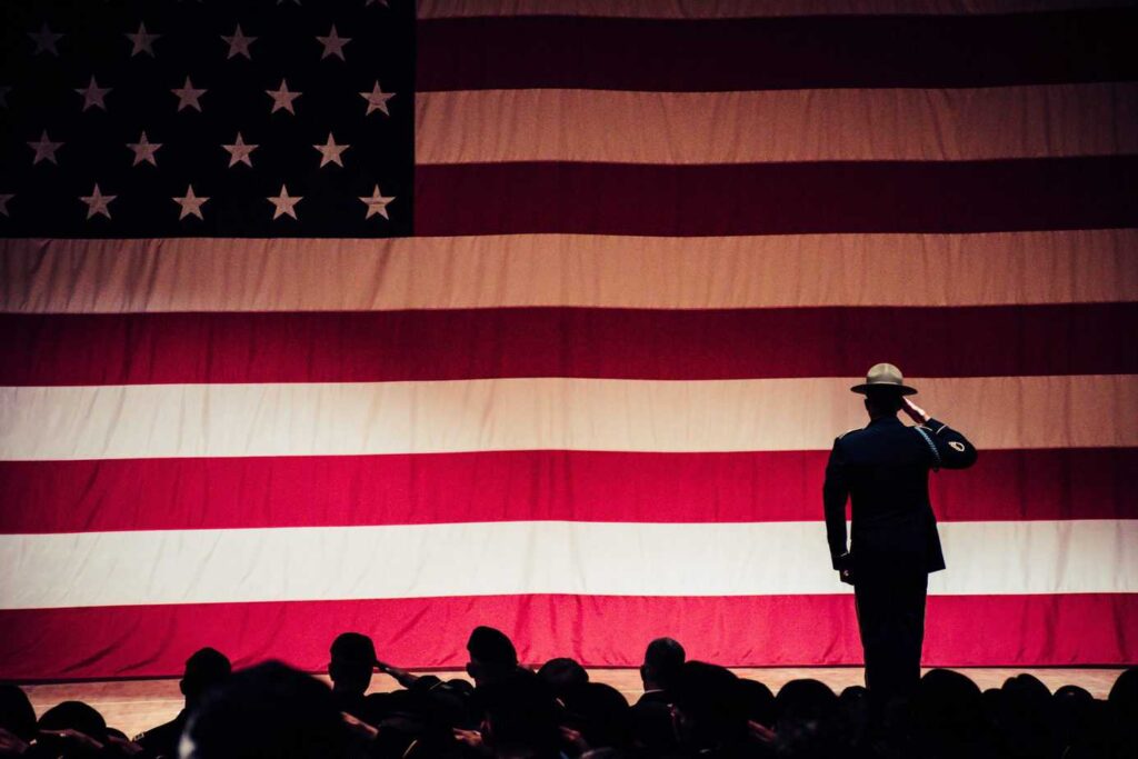 Full American flag banner with service member saluting