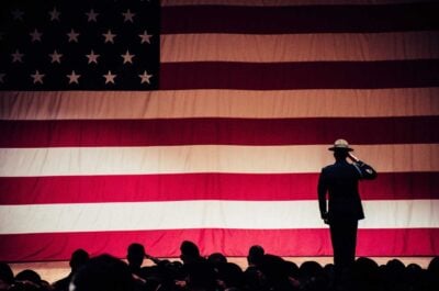 Full American flag banner with service member saluting