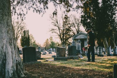 Man placing flowers on gravestone at cemetery