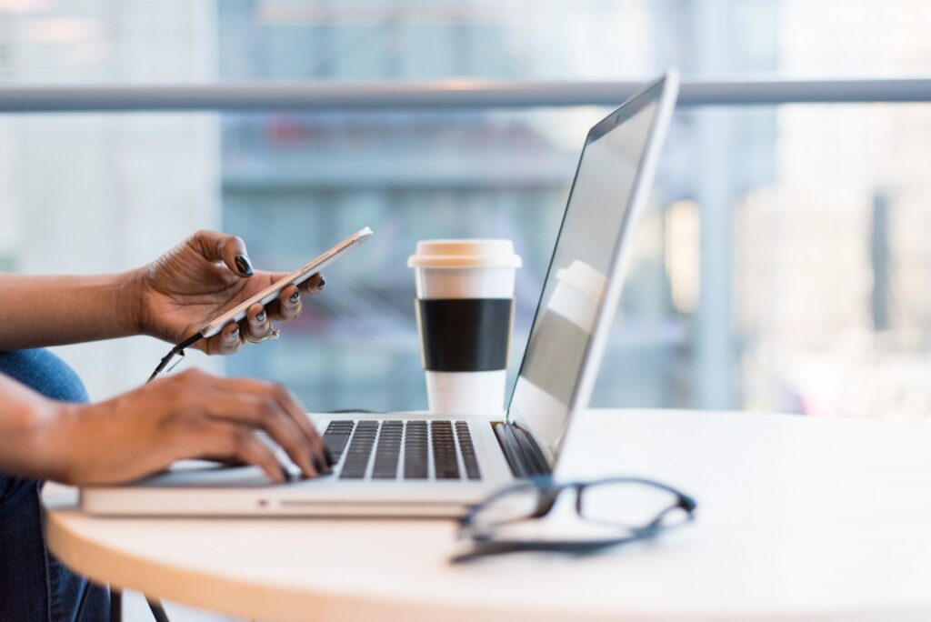 Person working on both phone and laptop at desk