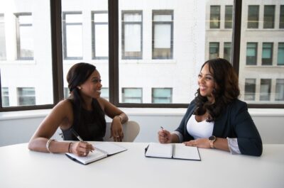 Two people smiling and writing in notebooks