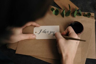 Person writing cursive "I love you" message in ink