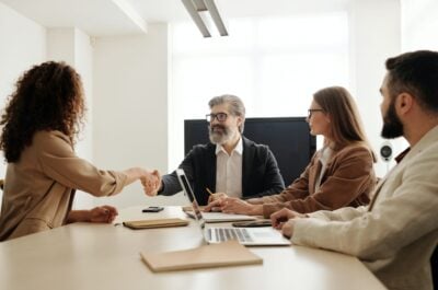 People shaking hands at conference table