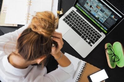 Person putting head in hands while looking at laptop