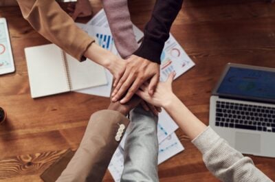 People placing hands together over meeting table