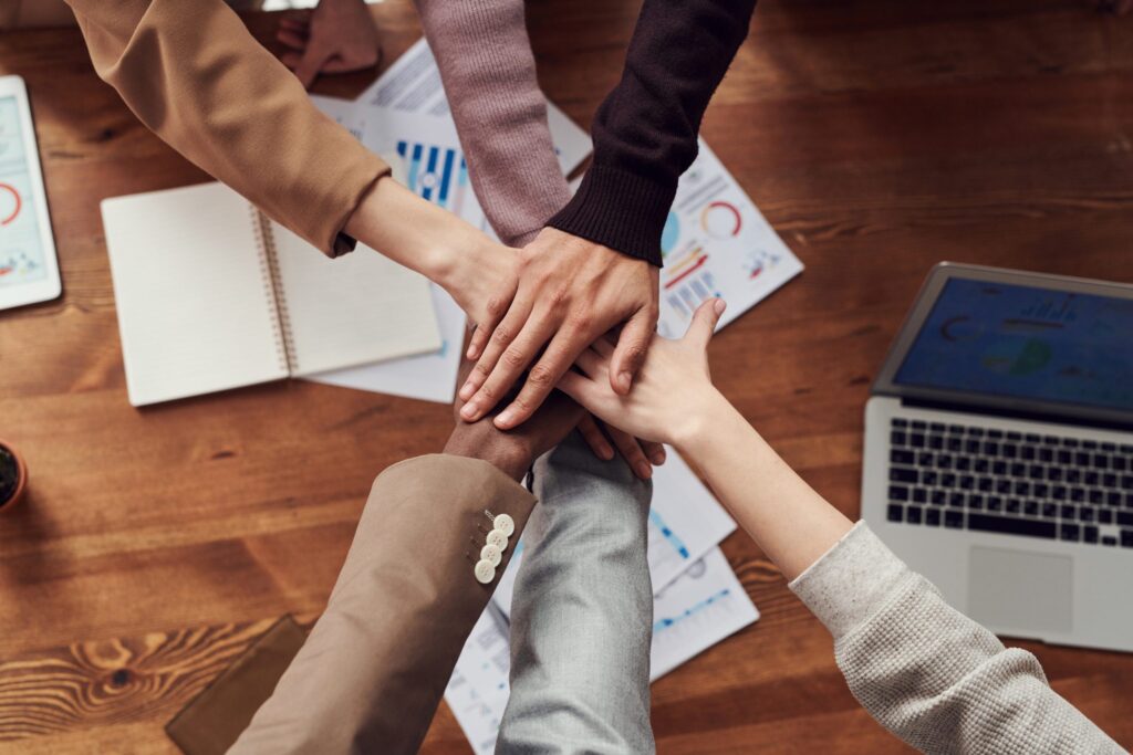 People putting hands together over meeting table